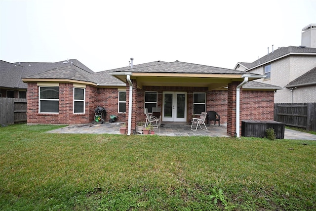 back of property with brick siding, a fenced backyard, french doors, a patio, and a lawn