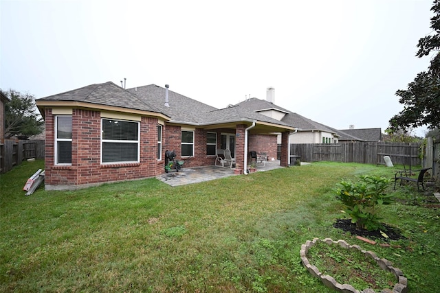back of house featuring brick siding, a fenced backyard, a yard, and a patio
