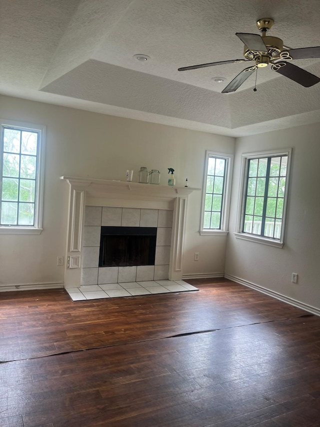 unfurnished living room featuring plenty of natural light, wood-type flooring, a ceiling fan, and a textured ceiling