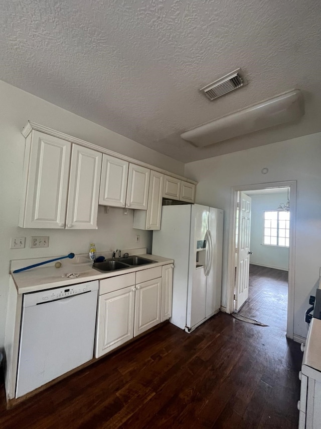kitchen with visible vents, white appliances, light countertops, a sink, and dark wood finished floors