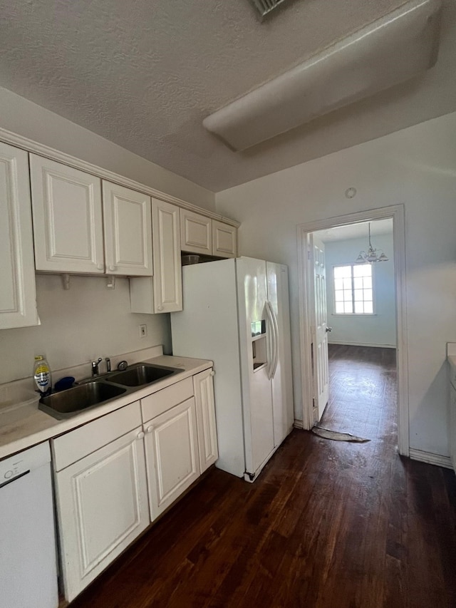 kitchen with a sink, dark wood finished floors, white appliances, and light countertops