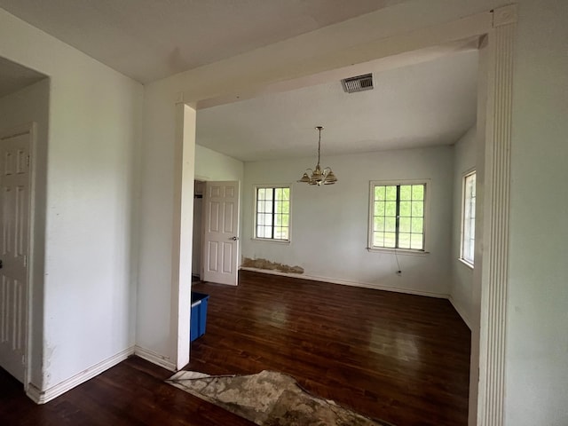 empty room featuring baseboards, visible vents, an inviting chandelier, and dark wood-type flooring