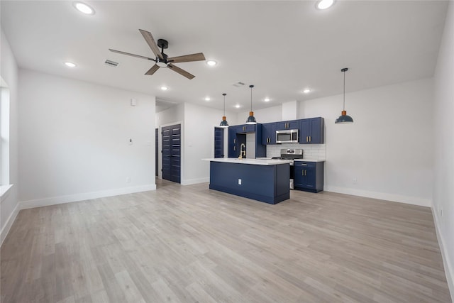 kitchen featuring appliances with stainless steel finishes, light countertops, a ceiling fan, open floor plan, and blue cabinets