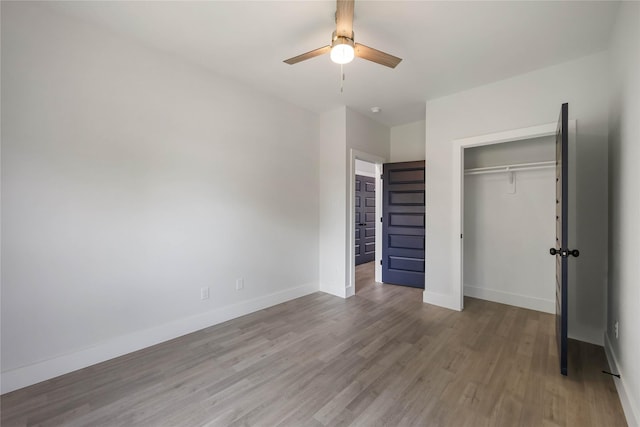 unfurnished bedroom featuring baseboards, ceiling fan, a closet, and wood finished floors