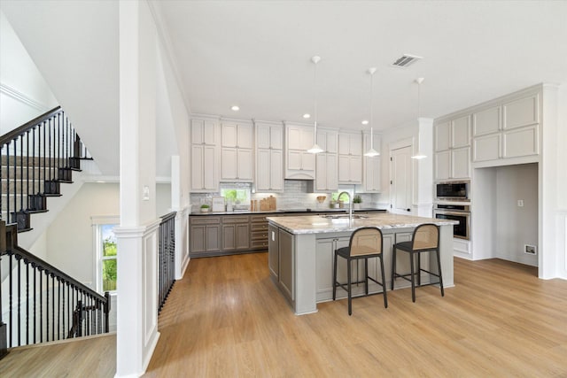 kitchen with oven, visible vents, built in microwave, and light wood-style floors