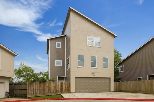 back of property featuring fence, stucco siding, driveway, and a garage