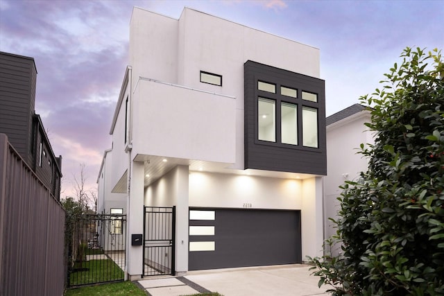 modern home featuring a garage, fence, stucco siding, a gate, and driveway