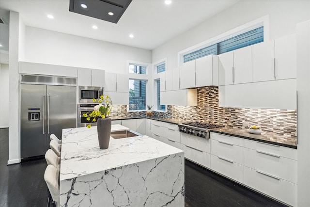 kitchen with built in appliances, modern cabinets, and a kitchen island with sink