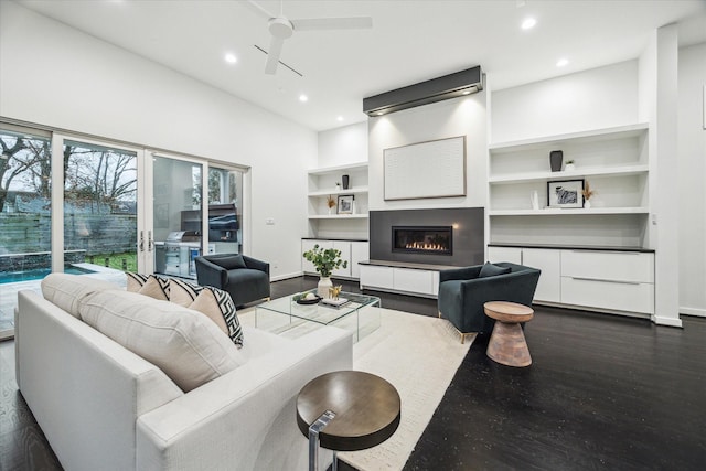 living room with built in features, a ceiling fan, baseboards, recessed lighting, and dark wood-type flooring