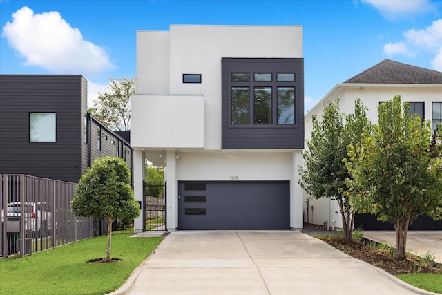 contemporary house featuring a garage, fence, a front yard, stucco siding, and concrete driveway