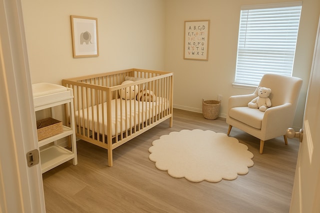bedroom featuring baseboards, wood finished floors, and a crib