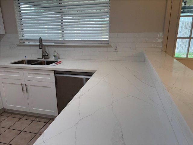 kitchen featuring white cabinets, light stone counters, a sink, dishwasher, and decorative backsplash