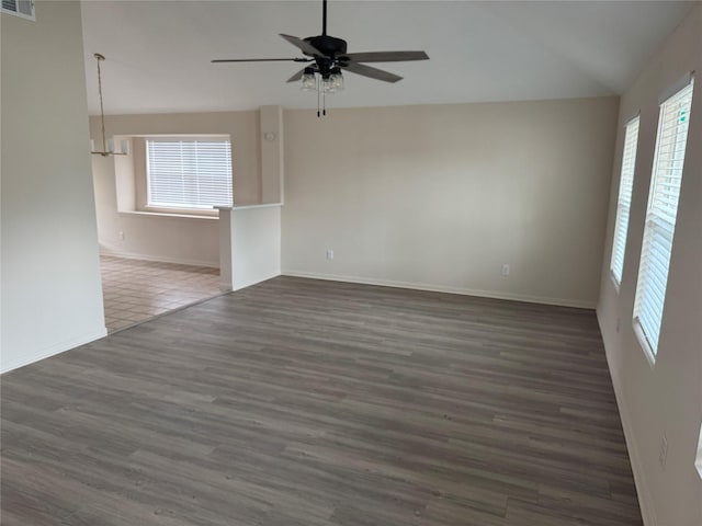 spare room featuring plenty of natural light, a ceiling fan, dark wood-style flooring, and vaulted ceiling