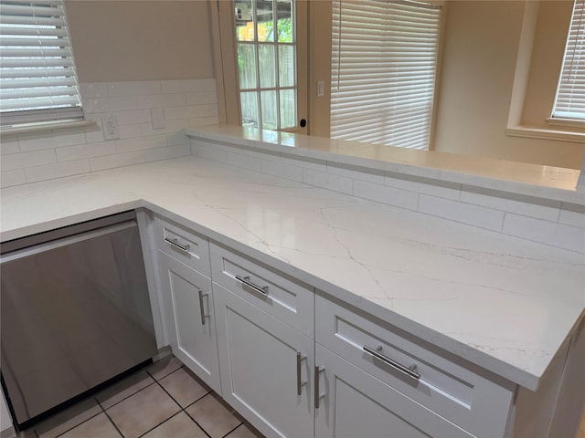 kitchen featuring light stone counters, dishwasher, and a healthy amount of sunlight