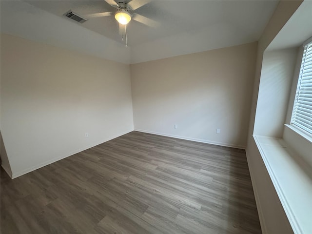 spare room featuring baseboards, a ceiling fan, dark wood finished floors, and visible vents