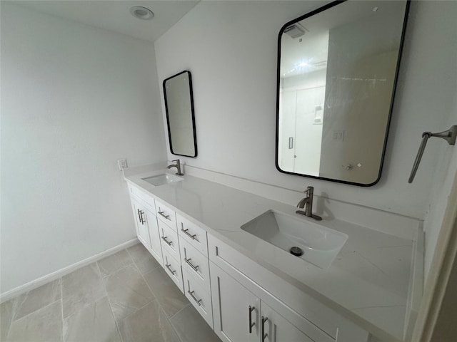 bathroom featuring baseboards, a sink, and double vanity
