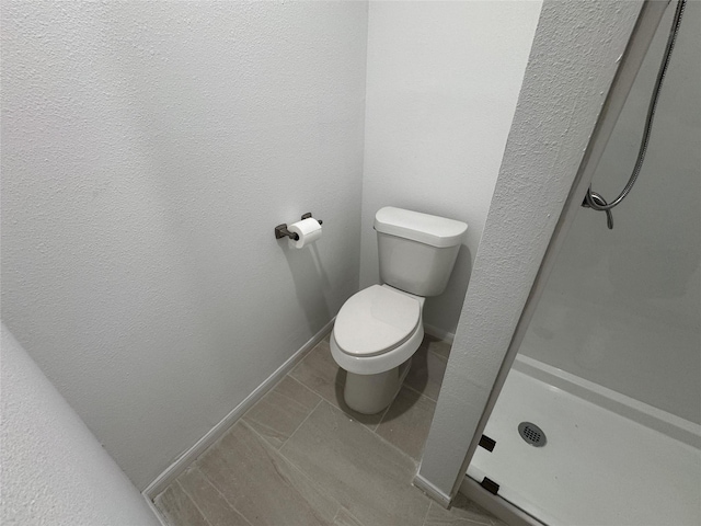 full bath with baseboards, a stall shower, and toilet