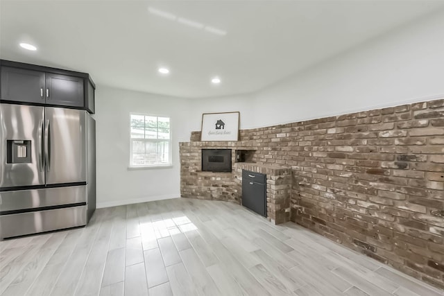 22 13th Ave N, Texas City, TX 77590 - kitchen with brick wall, light wood-style flooring, stainless steel fridge with ice dispenser, and a fireplace