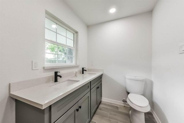 22 13th Ave N, Texas City, TX 77590 - bathroom with double vanity, wood finished floors, a sink, baseboards, and toilet