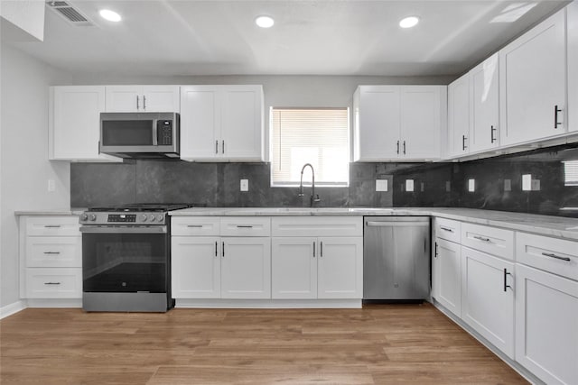 18330 Cape Bahamas Ln, Houston, TX 77058 - kitchen featuring visible vents, white cabinets, tasteful backsplash, a sink, and stainless steel appliances