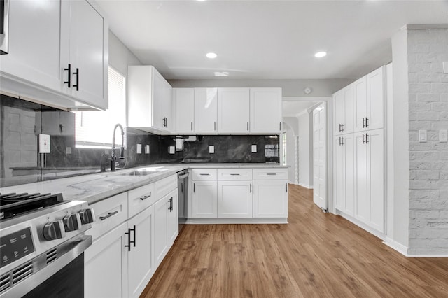 18330 Cape Bahamas Ln, Houston, TX 77058 - kitchen with light stone countertops, appliances with stainless steel finishes, a sink, light wood-style flooring, and decorative backsplash