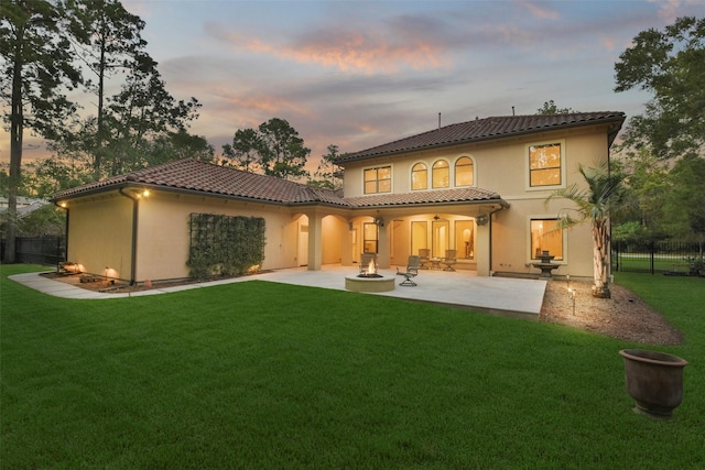 4014 N Rondelet Dr, Spring, TX 77386 - back of house at dusk with fence, stucco siding, a lawn, a patio, and a tiled roof