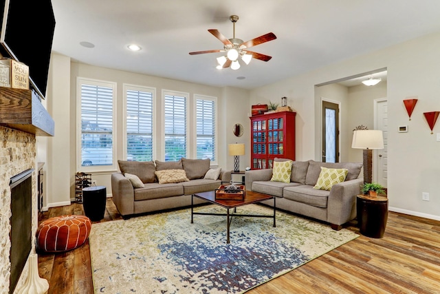 living area with a fireplace, a ceiling fan, baseboards, recessed lighting, and wood finished floors