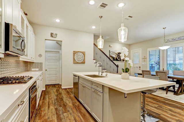 kitchen featuring visible vents, a sink, appliances with stainless steel finishes, and a breakfast bar area