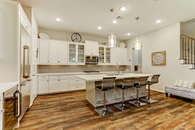 kitchen with a sink, beverage cooler, dark wood finished floors, stainless steel microwave, and visible vents