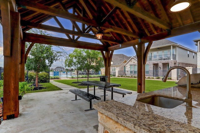 view of property's community with a lawn, a patio area, a sink, a gazebo, and fence