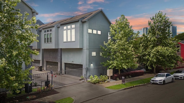 contemporary house with concrete driveway, fence, and a garage