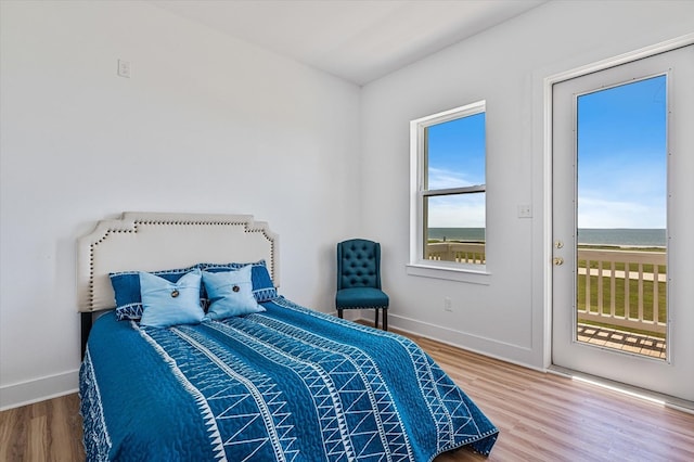 bedroom featuring baseboards, access to outside, and wood finished floors