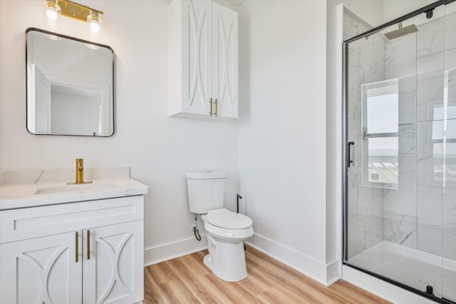 bathroom featuring vanity, toilet, baseboards, wood finished floors, and a stall shower