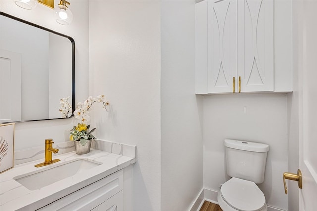 half bath featuring toilet, baseboards, wood finished floors, and vanity