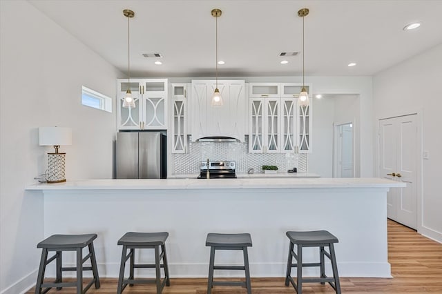 kitchen with pendant lighting, glass insert cabinets, white cabinets, backsplash, and stainless steel appliances