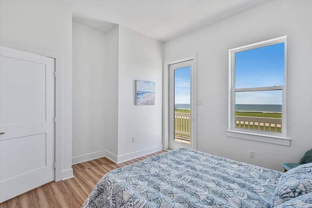 bedroom featuring access to outside, baseboards, and wood finished floors