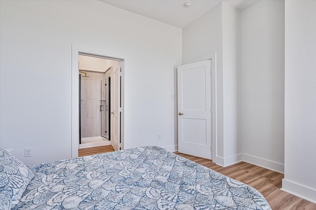 bedroom featuring connected bathroom, baseboards, and wood finished floors