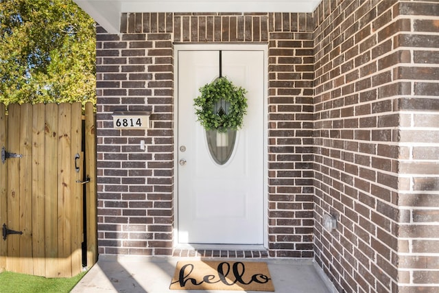 property entrance featuring brick siding and fence