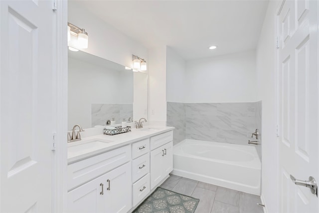 bathroom featuring double vanity, recessed lighting, a sink, and a garden tub