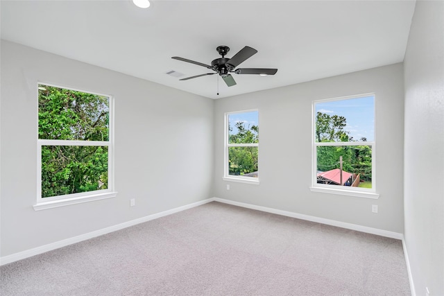 carpeted spare room with baseboards, visible vents, and ceiling fan