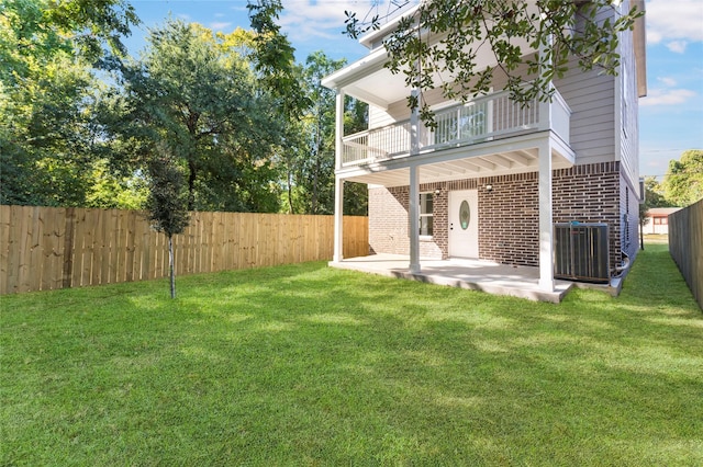 back of property featuring central AC unit, brick siding, a balcony, a fenced backyard, and a patio