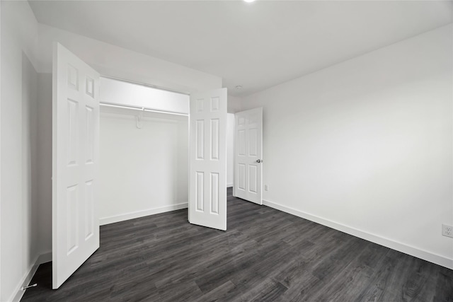unfurnished bedroom with baseboards, a closet, and dark wood finished floors