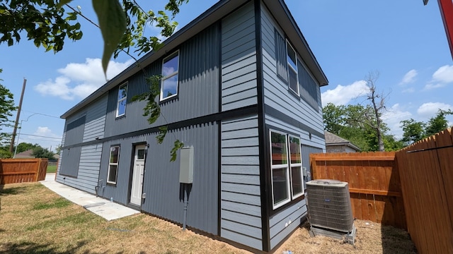 view of side of home featuring central air condition unit, a lawn, and fence