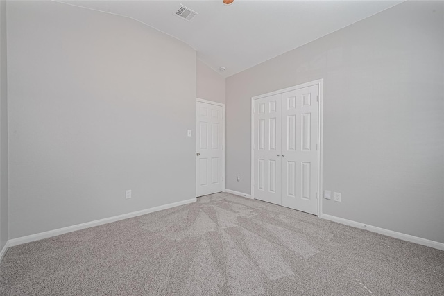 unfurnished bedroom featuring carpet floors, baseboards, visible vents, and lofted ceiling