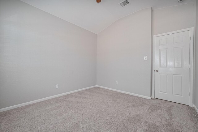 carpeted empty room with visible vents, baseboards, and lofted ceiling