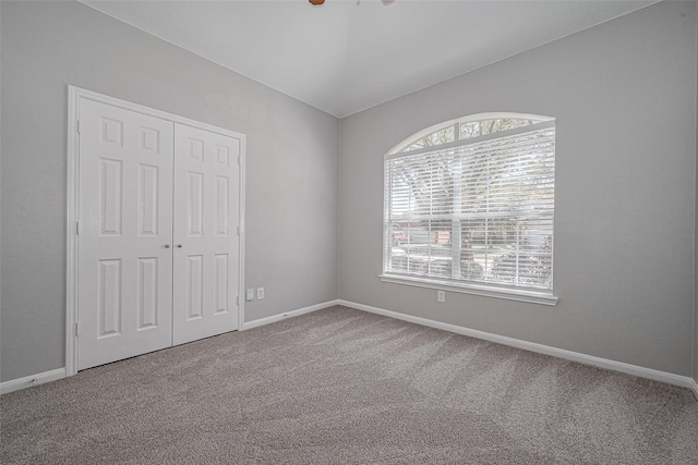 unfurnished bedroom featuring baseboards, carpet, and a closet