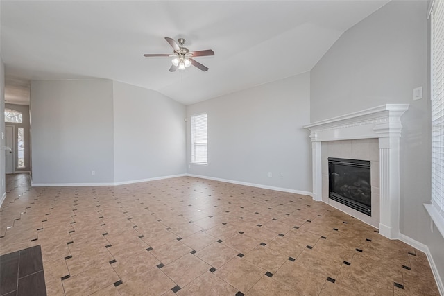 unfurnished living room featuring ceiling fan, vaulted ceiling, a tiled fireplace, and baseboards