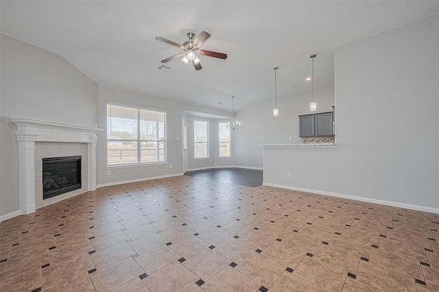 unfurnished living room with ceiling fan with notable chandelier, baseboards, a fireplace, and vaulted ceiling