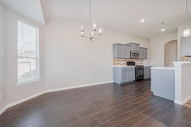 kitchen featuring a healthy amount of sunlight, gray cabinetry, light countertops, black gas range oven, and stainless steel microwave