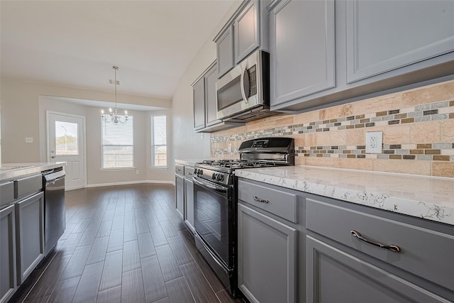 kitchen with appliances with stainless steel finishes, an inviting chandelier, baseboards, tasteful backsplash, and gray cabinetry